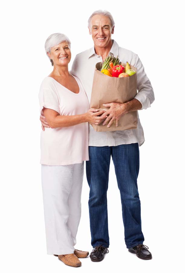 Smiling older couple holding a grocery bag full of produce